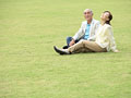芝生に座るシニア夫婦