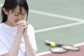 テニスラケットと祈る女子高生