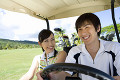 ゴルフカートに乗る日本人カップル