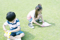 芝生の上で折り紙をする男の子と女の子