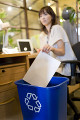 リサイクルBOXに紙を入れる女性