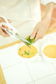 スープの浮き身にチャイブを刻む女性の手