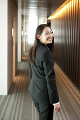 オフィスの廊下で笑顔で振り返るスーツ姿の女性