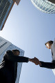 オフィス街で握手をする２人のビジネスマン達