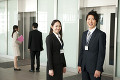 オフィスビルのエレベーター前でこちらに微笑むビジネスマン達