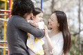 公園で赤ちゃんを抱く父親と笑顔で寄り添う母親