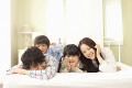 ベッドの上で仲良く微笑むパジャマ姿の４人家族