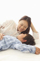 ベッドの上で息子と笑顔で話す若い母親