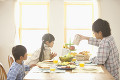 朝食でテーブルに腰掛けて会話をする父親と子供達