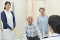 病院の診察室で笑顔で医師と話しをするシニア夫婦