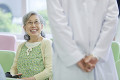 病院のロビーで笑顔で医師と会話するシニア女性