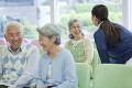 病院のロビーで笑顔で看護婦と会話するシニア女性