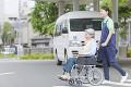 横断歩道を渡る車いすに乗ったシニア女性と女性介護士