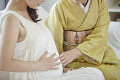 妊婦とそのお腹を触るシニア女性