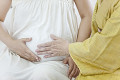 妊婦とそのお腹を触るシニア女性