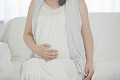 ソファに座りお腹を触る妊婦