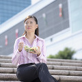 階段に座ってサラダを食べているビジネスウーマン