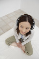 ベッドの上で音楽を聴いている日本人女性
