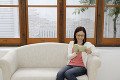 ソファーに座って読書をする日本人女性