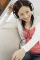 ソファーに座って音楽を聴いている日本人女性