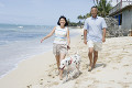 ビーチを犬と散歩するシニア夫婦