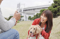 犬を抱っこする女性と携帯のカメラで撮る男性