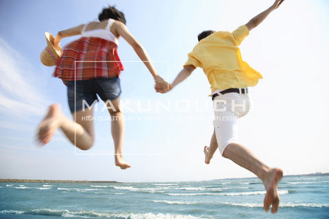 海に向かってジャンプするカップル
