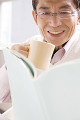 本を読みながらマグカップを持っている男性