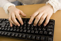 パソコンのキーボードを打つ女性の手元