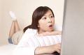 ノートパソコンのモニターを見て驚く女性