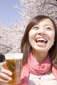 桜の下でビールを飲む女性