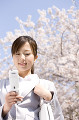 桜の下で携帯電話のメールを読む女性