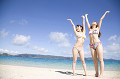 浜辺で万歳をしている水着姿の女性2人