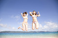 浜辺でジャンプする水着を着た2人の女性