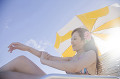 浜辺で日焼止めを身体に塗っている水着姿の女性
