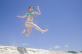 砂浜でジャンプする水着女性