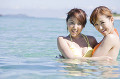 海に入って遊ぶ水着女性2人