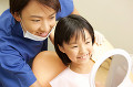 鏡で治療後の確認する男性歯科医と女の子