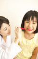 女の子に歯磨きの指導をする女性歯科医