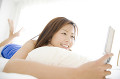 ベッドの上で携帯電話のメールを確認している女性