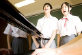 ピアノに合わせて歌う中学生男女