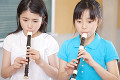 音楽室でリコーダーを吹く小学生2人