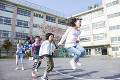 大縄跳びをする小学生4人と女性教師