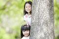 木の陰から顔を出す2人の女の子