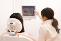 モニターを見ながら女性患者に説明する歯科衛生士の後姿