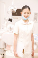 デンタルユニットの前に立ち微笑む歯科衛生士
