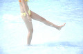 水を蹴り上げる水着姿の女性の足下