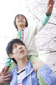 父親に肩車をしてもらい桜に触れようとする笑顔の男の子