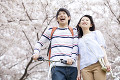 桜並木を歩く笑顔のカップル