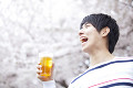 桜の下でビールを飲む笑顔の男性